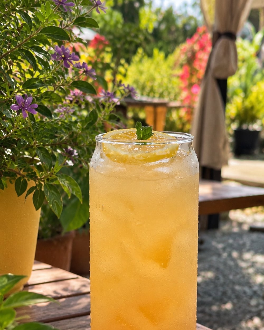Limonada de jengibre y miel con hielo, rodaja de limón y menta en una mesa del jardín