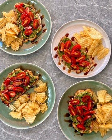 Tostadas mediterráneas con pesto, tomates y glaseado balsámico, servidas con papitas